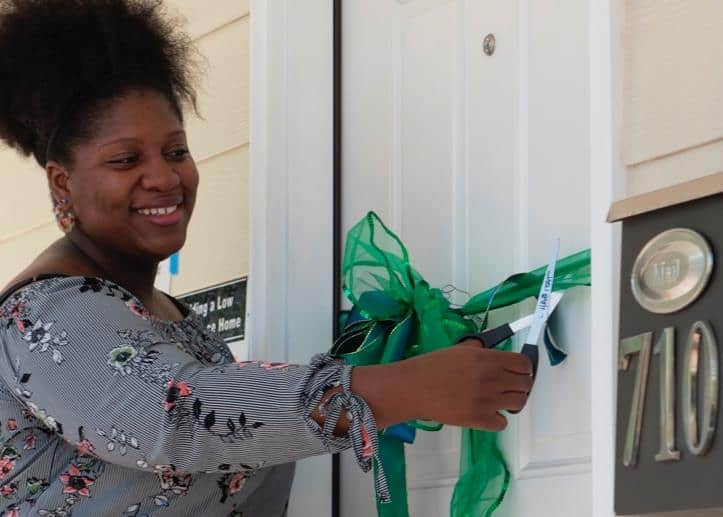 Tanae Lawal cutting the ribbon on the door to her new home in Cambridge